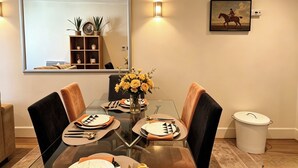 A dining area with a glass table, chairs, and a vase of flowers. - Cosy 2BRs Apt w/AC and balcony near Vauxhall (London)