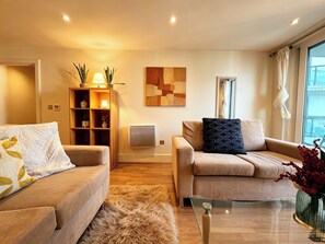A modern living room with two sofas, a coffee table, a rug, a wall-mounted air conditioner, and a painting. - Cosy 2BRs Apt w/AC and balcony near Vauxhall (London)