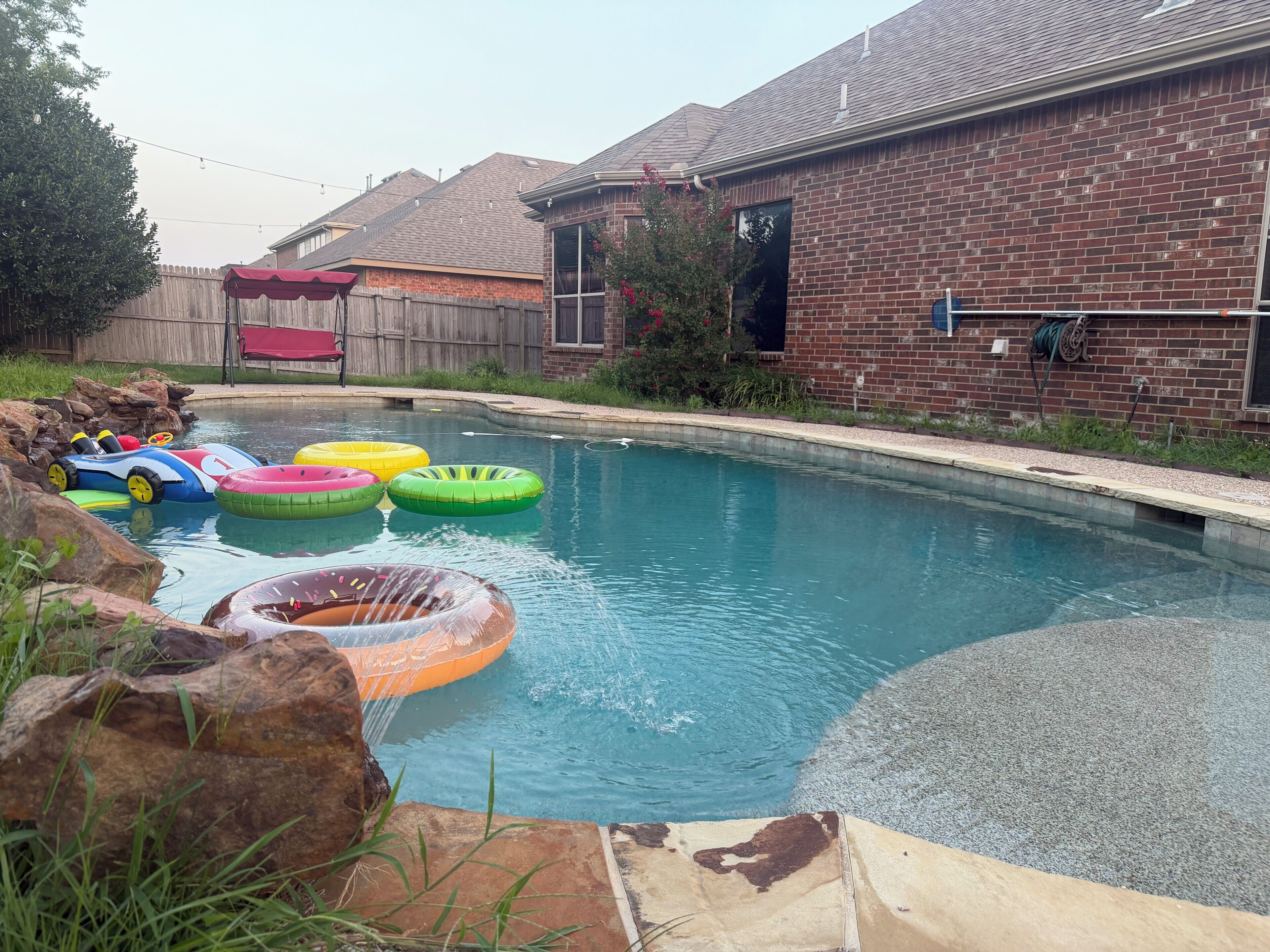Una piscina con flotadores inflables y una terraza de madera.
