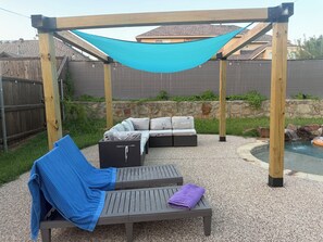 A covered outdoor seating area with a hammock, a bench, and a sofa with cushions. - Welcoming 4BR Luxury house with private POOL in charming Forney (Forney)