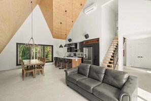 Et moderne interiør med spiseplads, sofa, køkken og trappe.