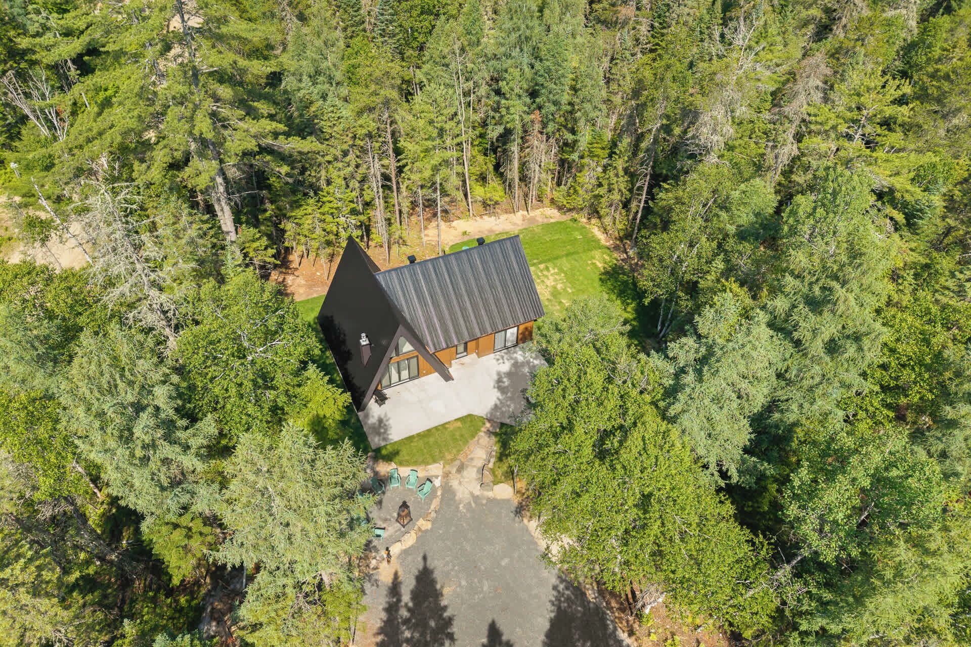 A modern house with a sloped roof, surrounded by dense forest.