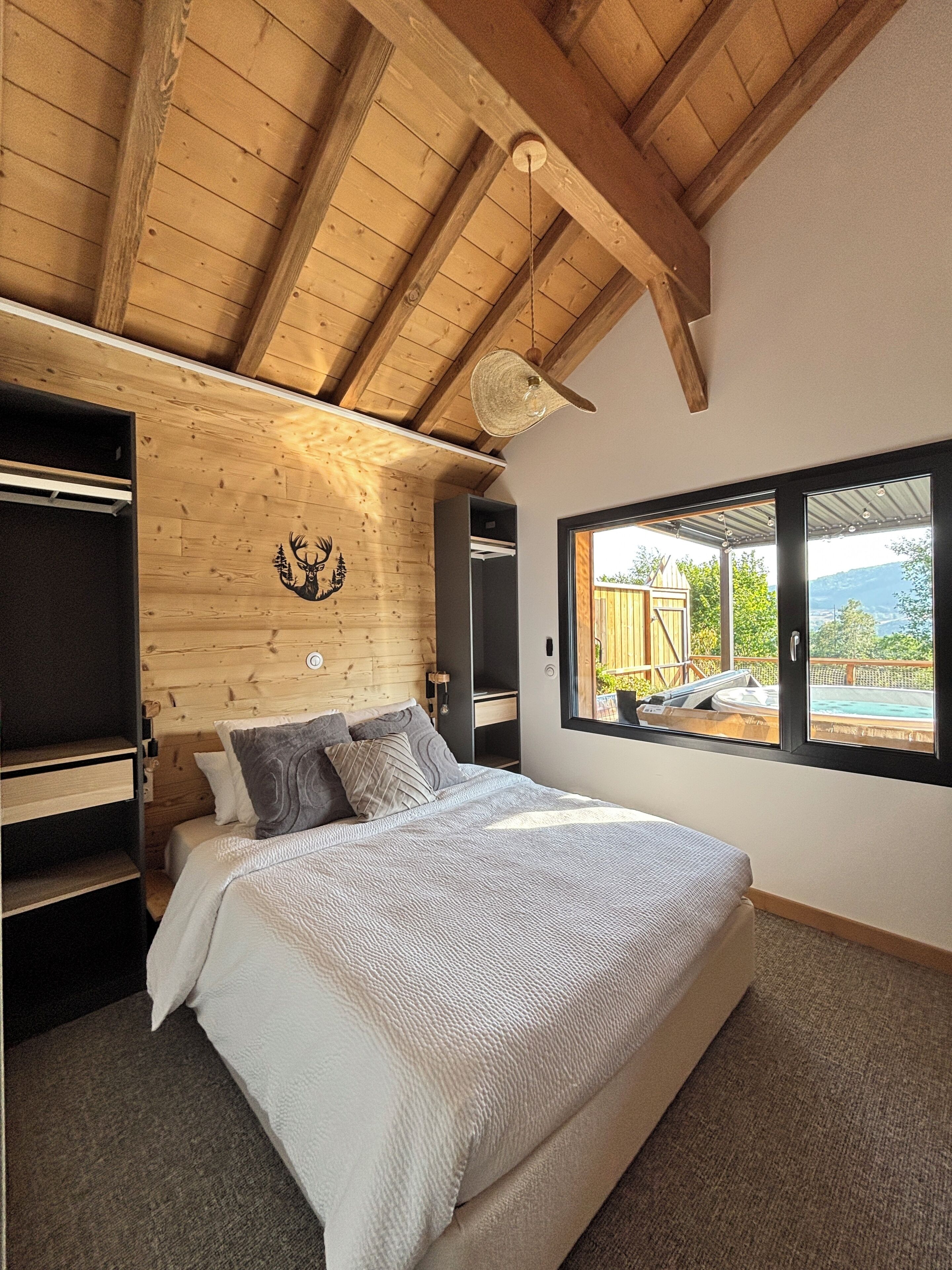 Ein Schlafzimmer mit einem Bett, Holzboden, einem Fenster und Blick ins Freie.