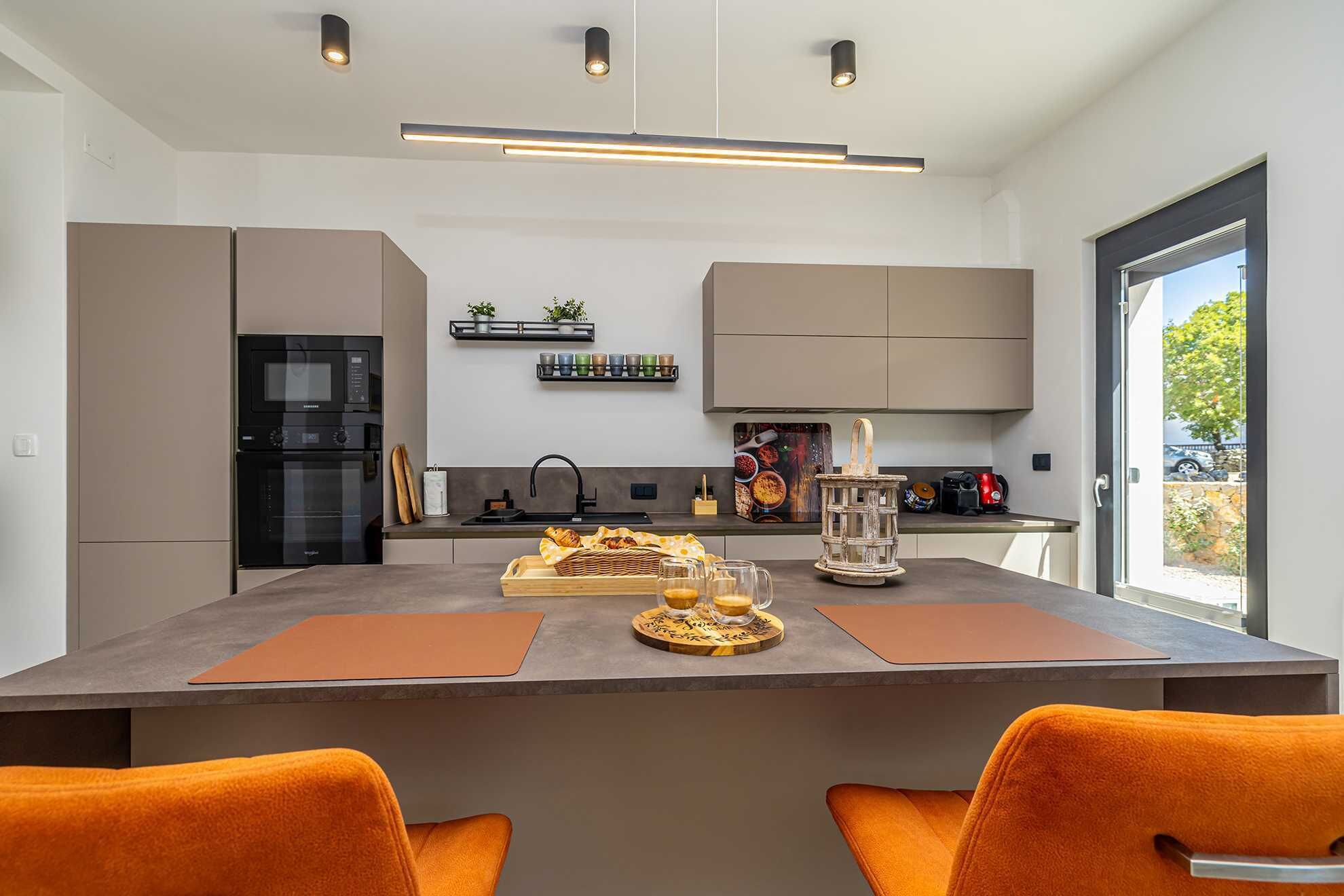 A modern kitchen with a central island, built-in appliances, and a view to the outside.