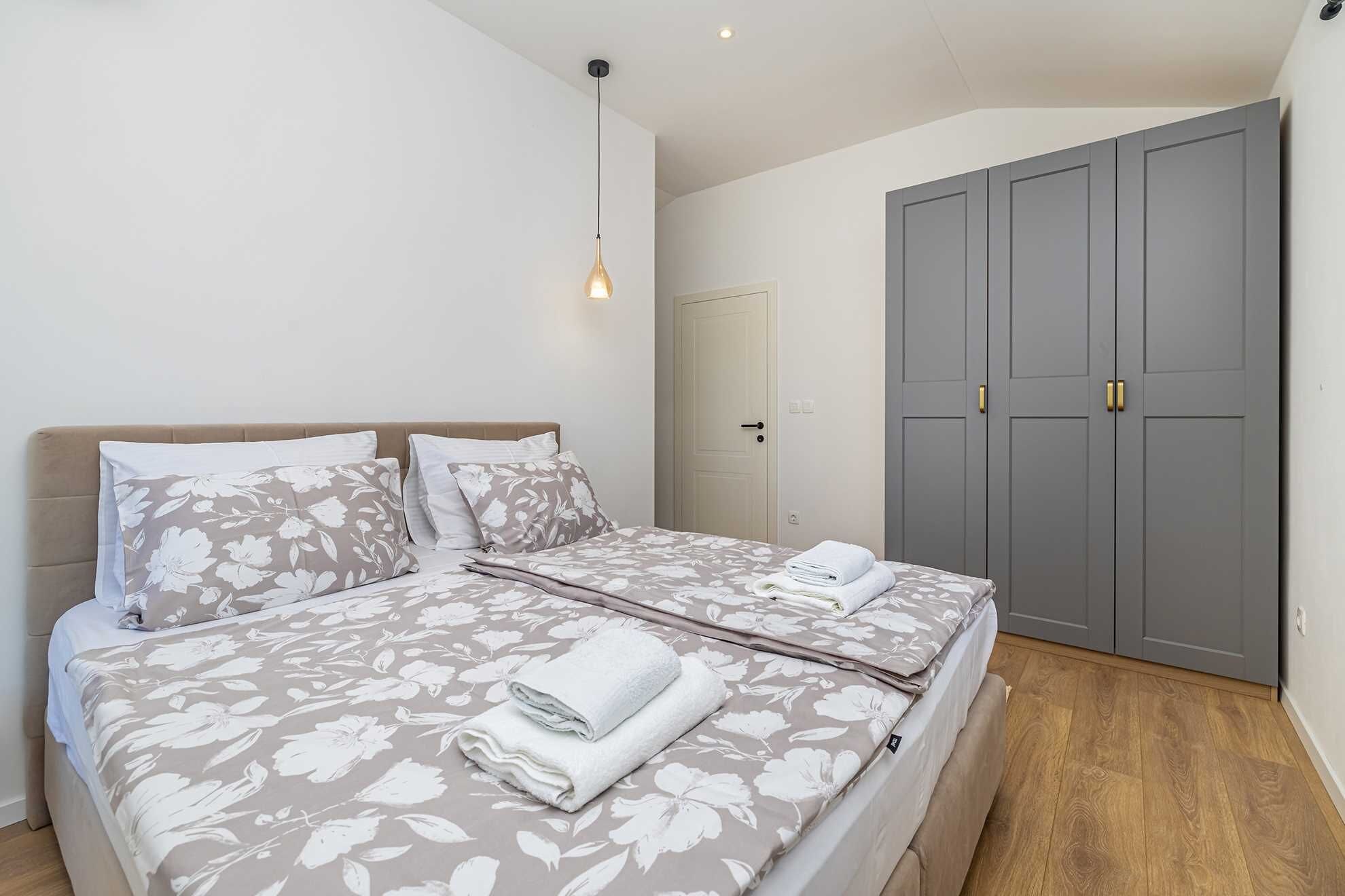 A bedroom with a bed, a wardrobe, and a hanging light fixture.