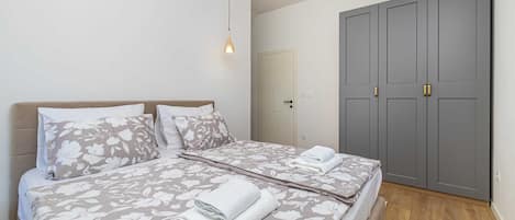 A bedroom with a bed, a wardrobe, and a hanging light fixture.