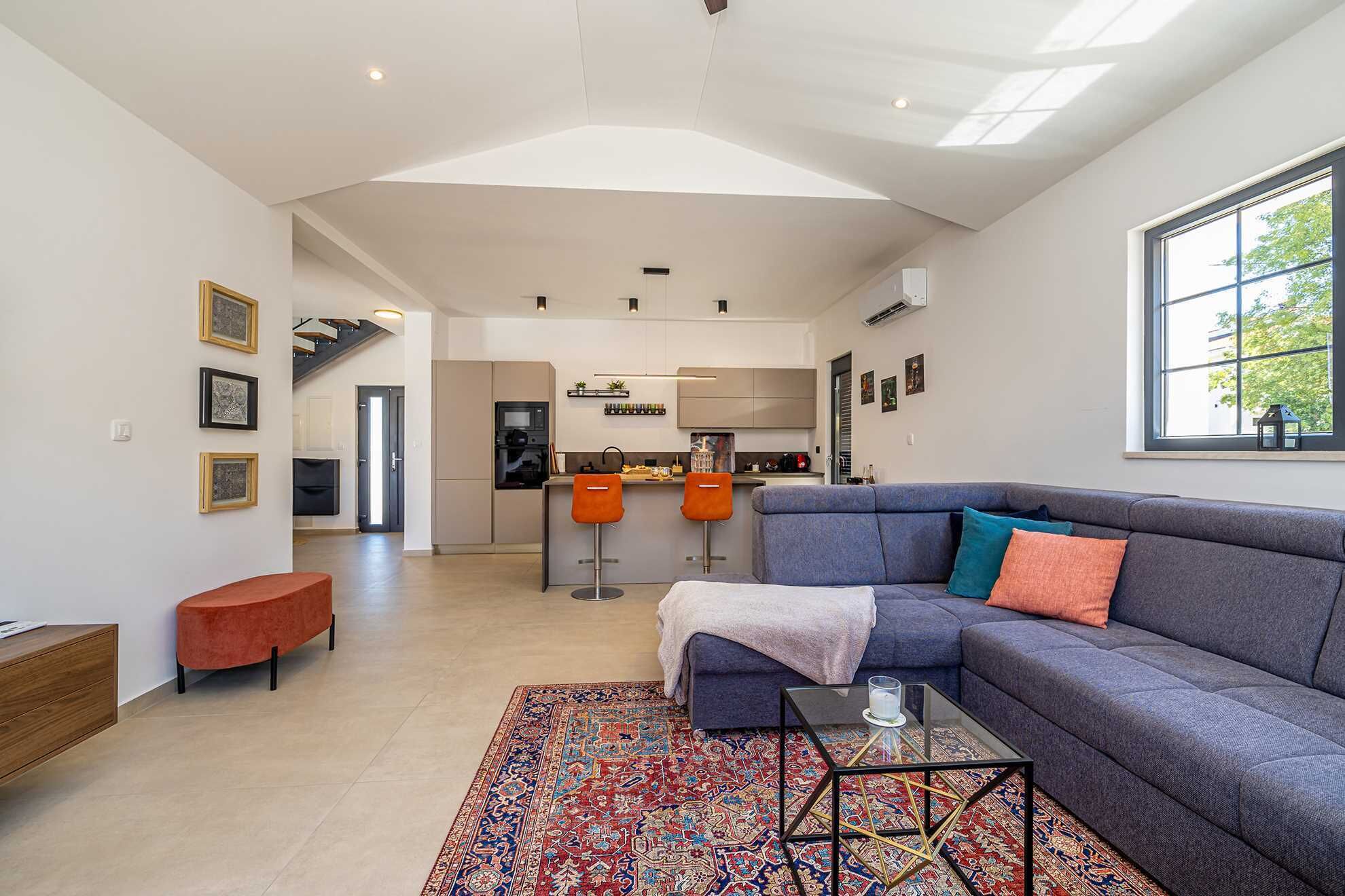 A modern living room with a grey sofa, a patterned rug, and a glass coffee table.