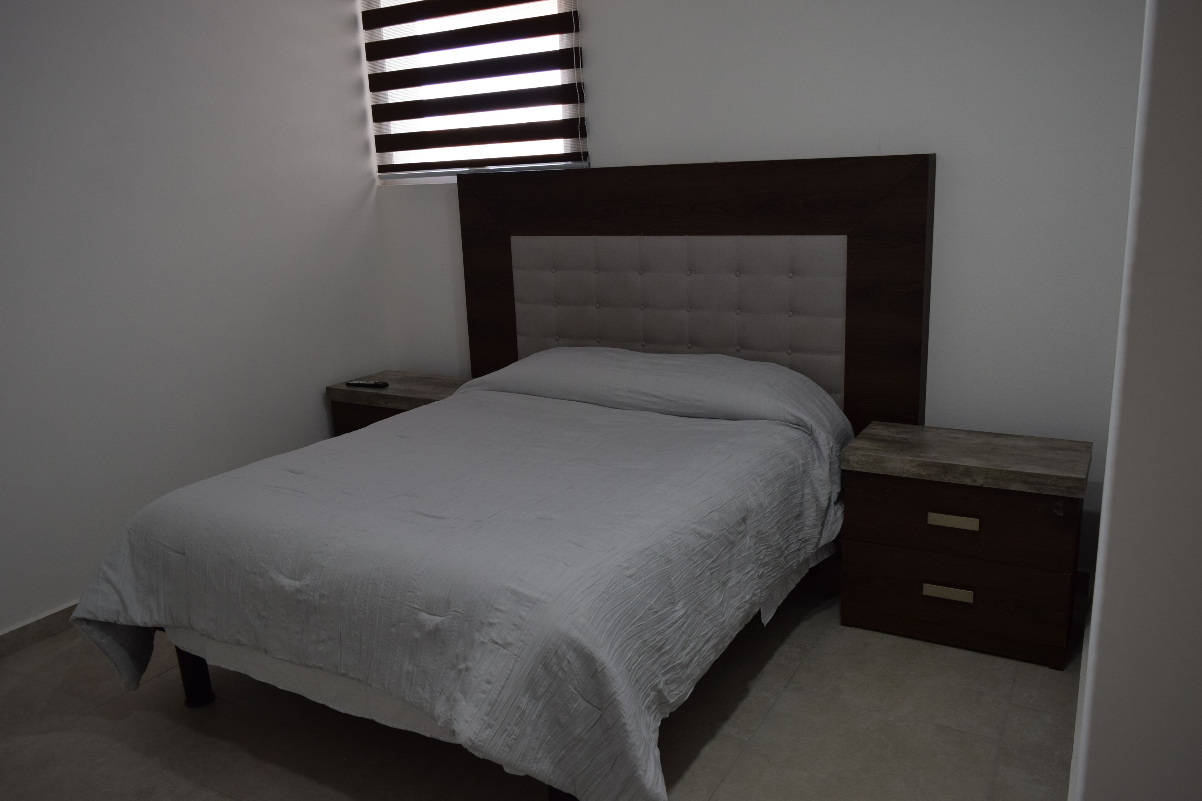 A single bed with a headboard, a nightstand, and a drawer unit.