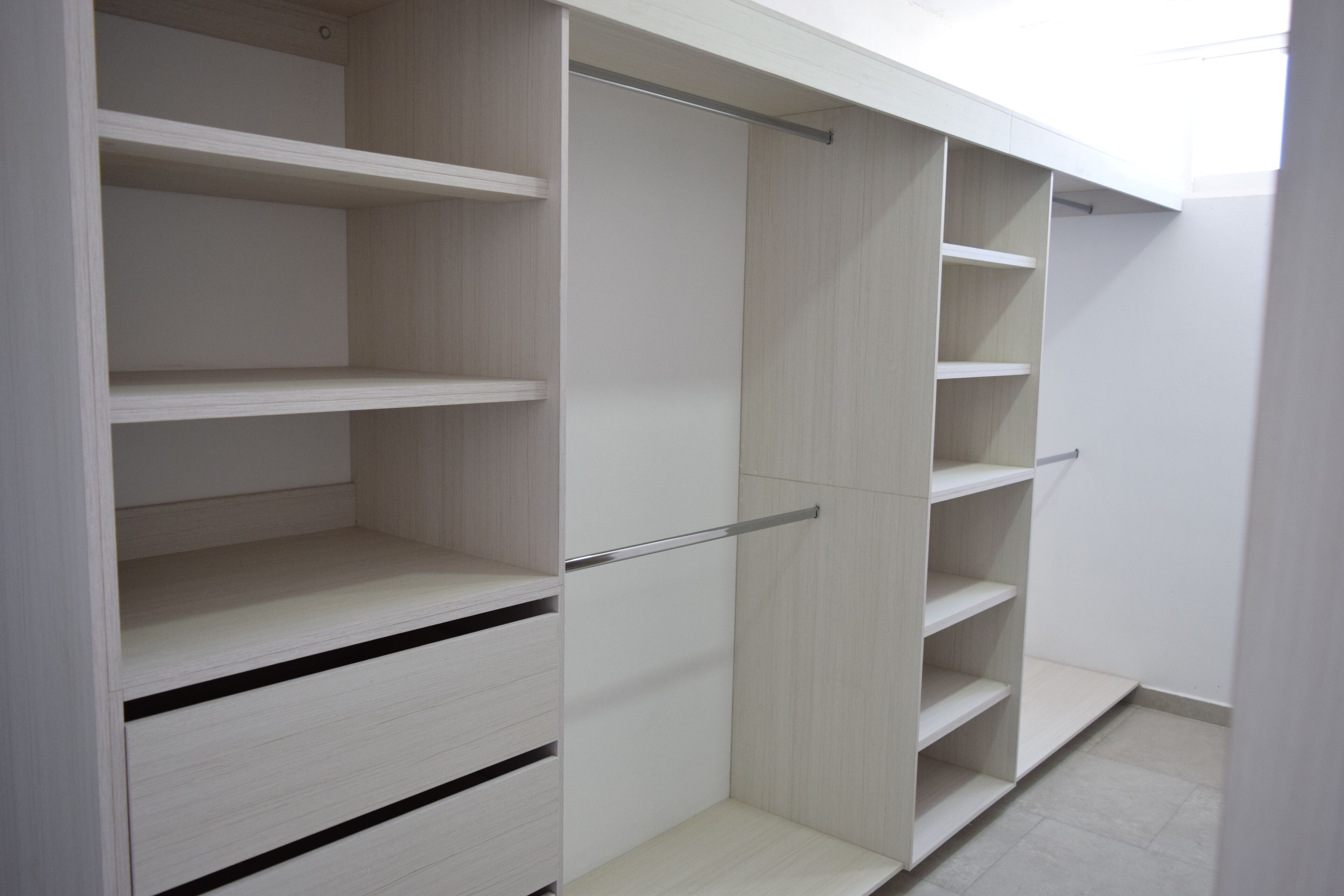 A walk-in closet with multiple shelves and drawers.