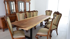 A dining room with a large wooden table surrounded by six chairs with ornate backs.