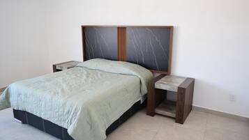 A bed with a headboard, two bedside tables, and a light-colored floor.