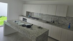 A modern kitchen with granite countertops, white cabinetry, a built-in oven, and a gas stove.