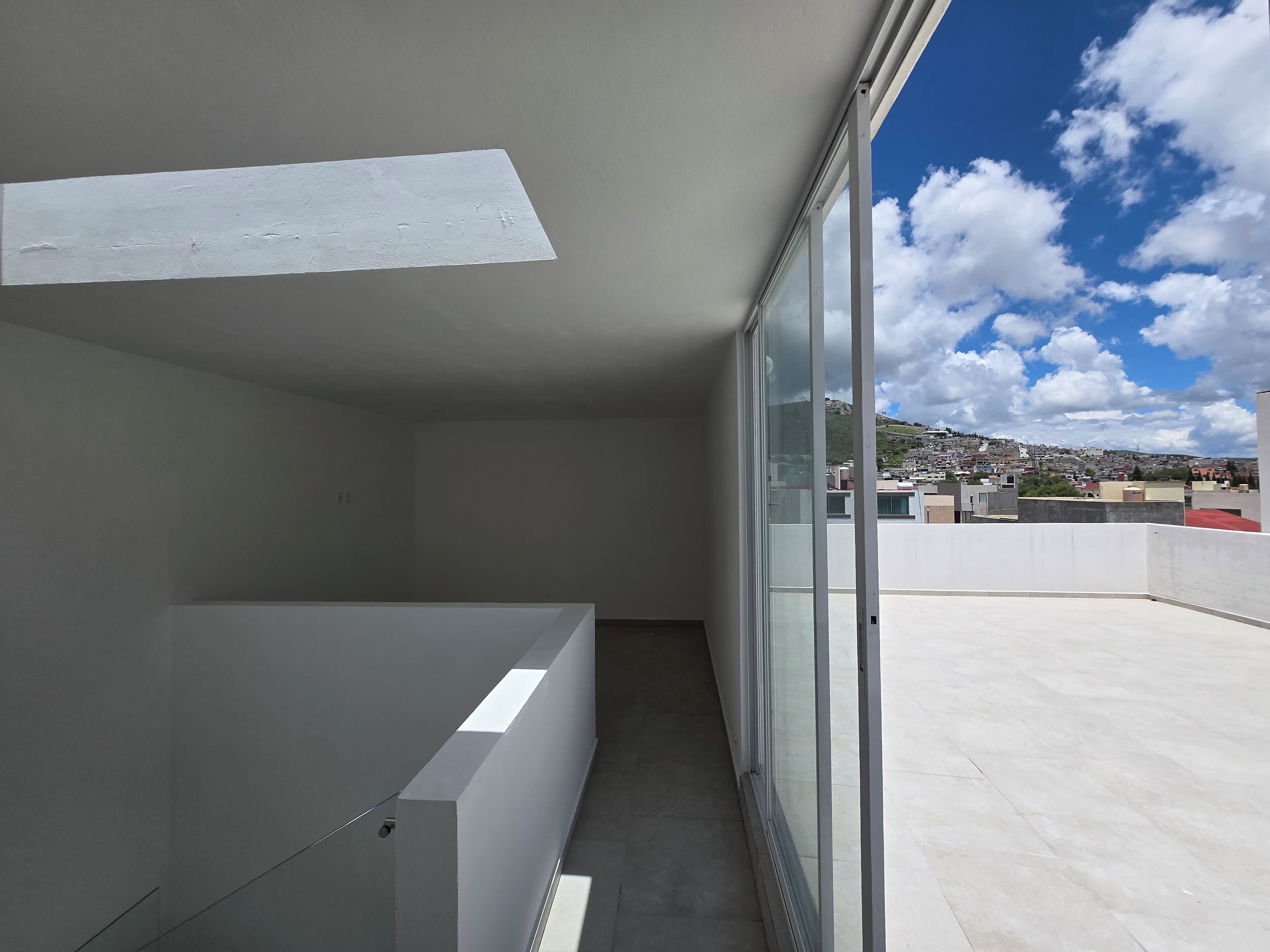 A balcony with a view of a cityscape and a clear sky.