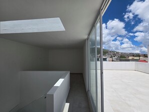 A balcony with a view of a cityscape and a clear sky.