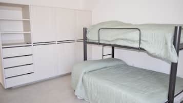 A bunk bed with a green mattress, a white wardrobe with multiple shelves, and a tiled floor.