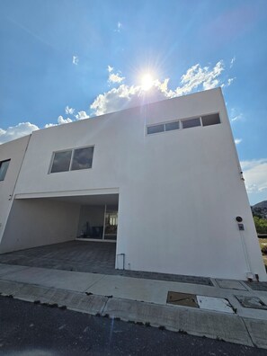 Un edificio moderno de dos pisos con techo plano, ventanas amplias y entrada a un garaje.
