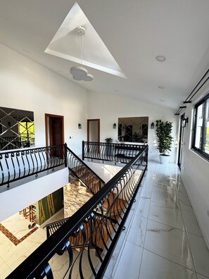 A spacious interior with a high ceiling, a central staircase, and a view of the outdoors.
