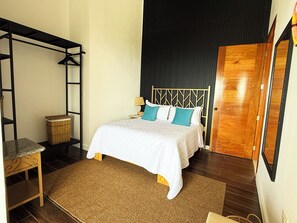 A bedroom with a bed, a wooden wardrobe, a hanging chair, and a small table.