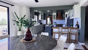 A modern kitchen with a central island, white cabinetry, and a dining area with a round table and chairs.