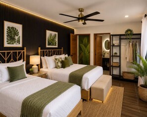 Ein Hotelzimmer mit zwei Betten, einem Deckenventilator, einem Kleiderschrank und einem durch eine offene Tür einsehbarer Badezimmer.