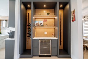 Eine kompakte Küche mit eingebautem Ofen, Holzregalen und einem Weinkühlschrank.