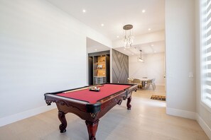 Ein Billardtisch in einem modernen Raum mit Essbereich und einer Treppe.