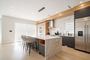 Eine moderne Küche mit einer Marmorinsel, Edelstahlgeräten und einer Bar mit Hockern.