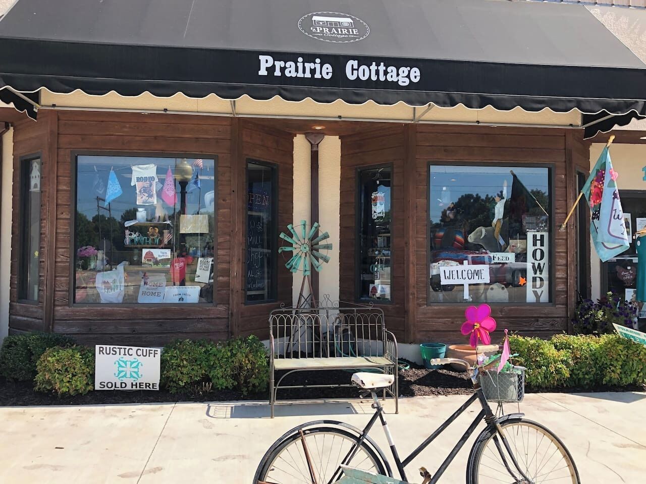 A storefront with a sign reading 'Prairie Cottage' and a 'Rustic Cuff' sign indicating a sale.