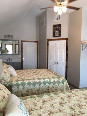 A bedroom with two beds, a ceiling fan, a mirror, and a door. - Prairie Cottage Queen steps to Pioneer Woman Merc (Pawhuska)