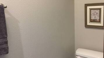 Un baño con inodoro, toallero y un cuadro en la pared.
