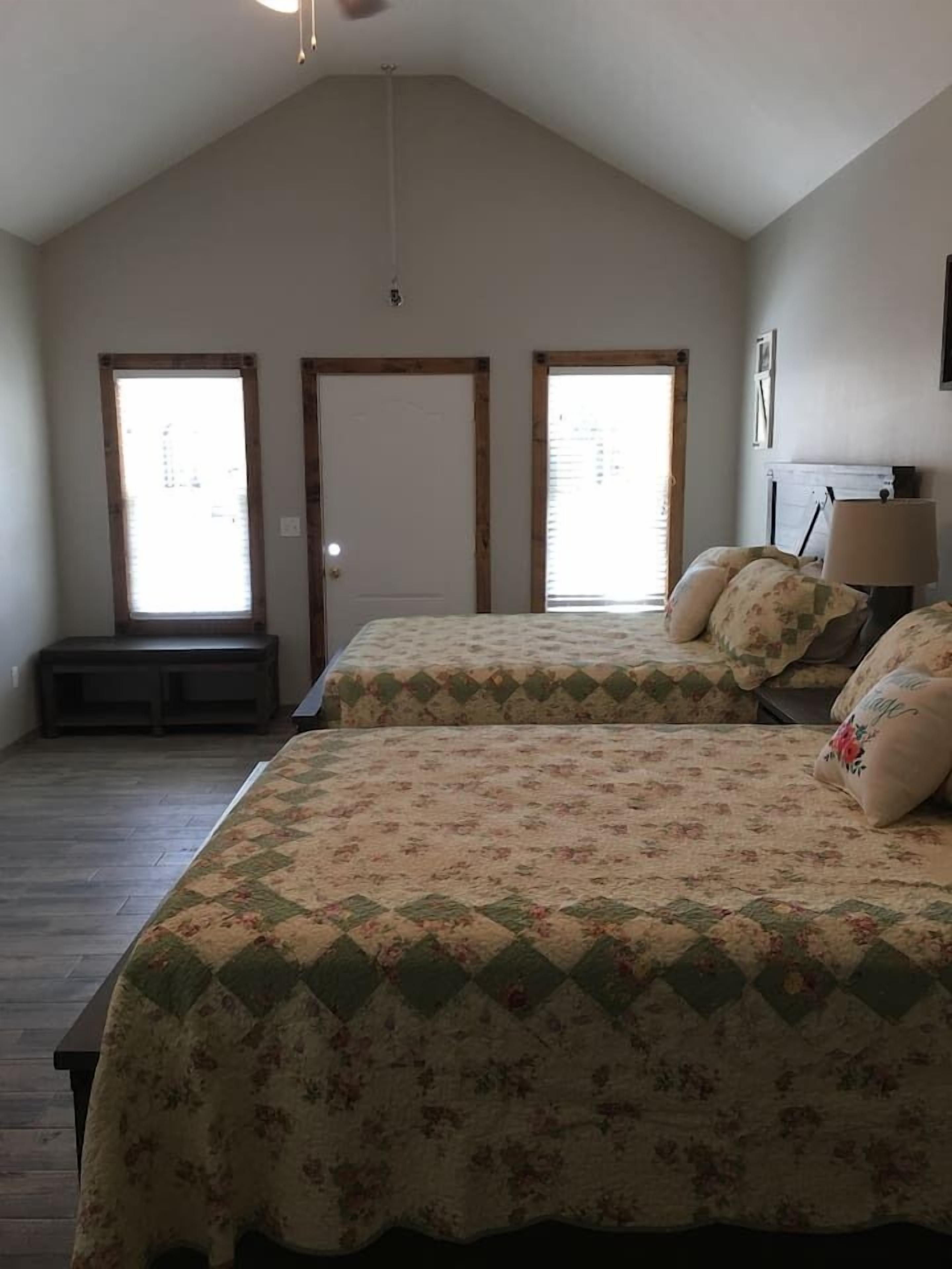 A bedroom with two beds, a bench, and a door.