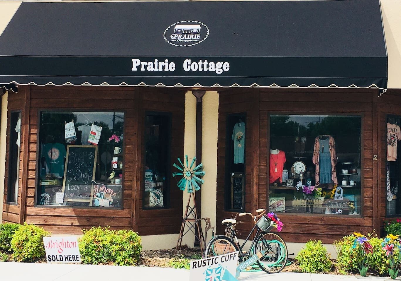 Una façana amb un rètol que diu 'Prairie Cottage' i un cartell que anuncia 'VENUT AQUÍ'.