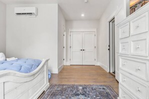 Ein Schlafzimmer mit einem Bett, einem Schminktisch, einem Kleiderschrank und einer Tür zu einem anderen Raum.
