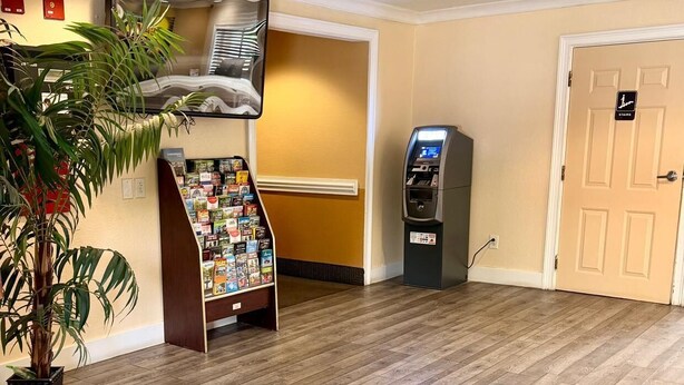 A lobby with a wooden floor, a reception desk, a vending machine, and a door marked 'Stairs'.