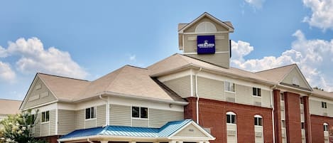 A hotel with a prominent 'Live in Lodge Extended Stay' sign, a covered entrance, and a parking lot.