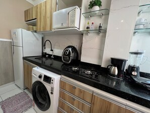 A compact kitchen with a washing machine, a stove, and a coffee maker. - 102 Acolhedor e aconchegante (Belém)