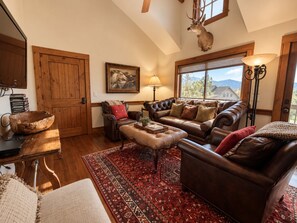 A cozy living room with leather sofas, a wooden coffee table, and a red patterned rug. - Dallas Chalet | 7BD 4.5BA with Hot Tub and Views! (Steamboat Springs)