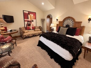 Ein Schlafzimmer mit einem großen Bett, einem Fernseher, einer Couch und einem Wanddekor.