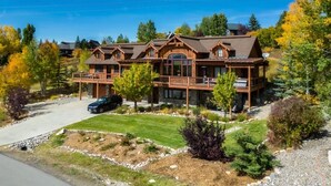 A large, two-story wooden cabin with a covered porch and a car parked in front. - Dallas Chalet | 7BD 4.5BA with Hot Tub and Views! (Steamboat Springs)