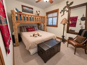 A bedroom with a bunk bed, a bedside table, a lamp, a chair, and a decorative mirror. - Dallas Chalet | 7BD 4.5BA with Hot Tub and Views! (Steamboat Springs)