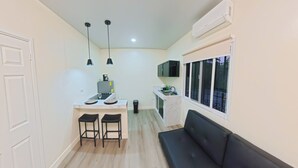 A compact kitchen with a dining area, a black sofa, and a window with a view.