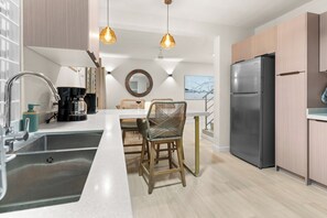 A modern kitchen with a built-in refrigerator, a coffee machine, and a dining area with wicker chairs. - Stylish, Comfortable, Private townhouse steps to Dover Beach & St. Lawrence Gap (Oistins)