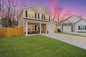 A two-story house with a covered front porch, a garage, and a fenced backyard. - BRING THE WHOLE CREW ★ 5BR HOME, SLEEPS 16 + HOT TUB, GAMES & BBQ (Charlotte)