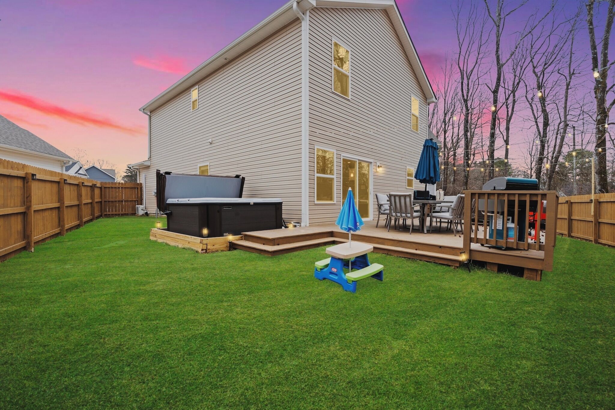 Un jardin avec un jacuzzi, des meubles de patio et une terrasse en bois.