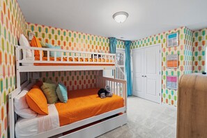 Een slaapkamer met stapelbedden, behang met een patroon, een witte deur en een plafondlamp.