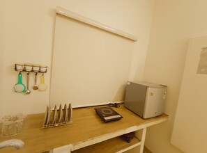 A kitchen counter with a scale, a refrigerator, and utensils hanging on a rack.