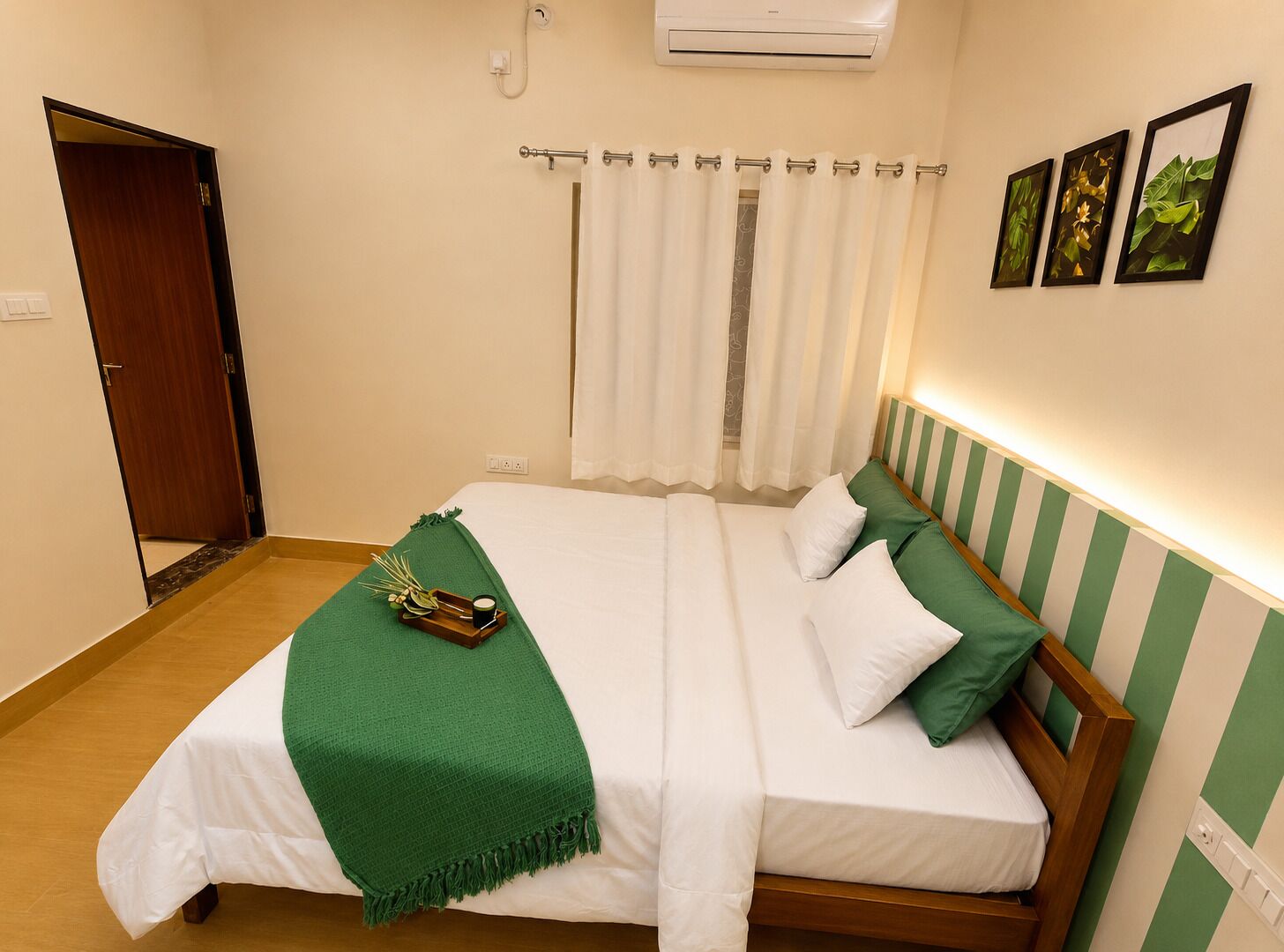 Habitació d'hotel amb llit, una manta verda, un safata amb una tassa i una cortina de bany.