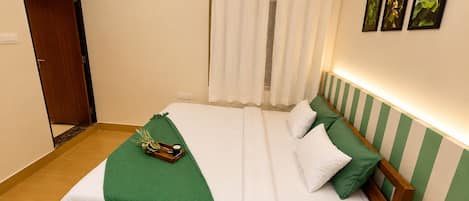 A hotel room with a bed, a green throw, a tray with a cup, and a shower curtain.