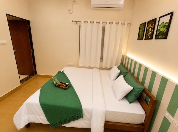 A hotel room with a bed, a green throw, a tray with a cup, and a shower curtain.