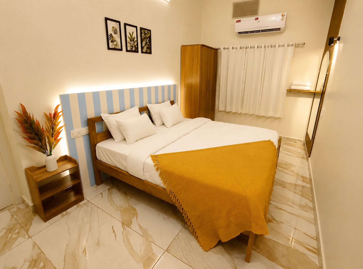 A bedroom with a bed, nightstand, and a wall-mounted air conditioner.